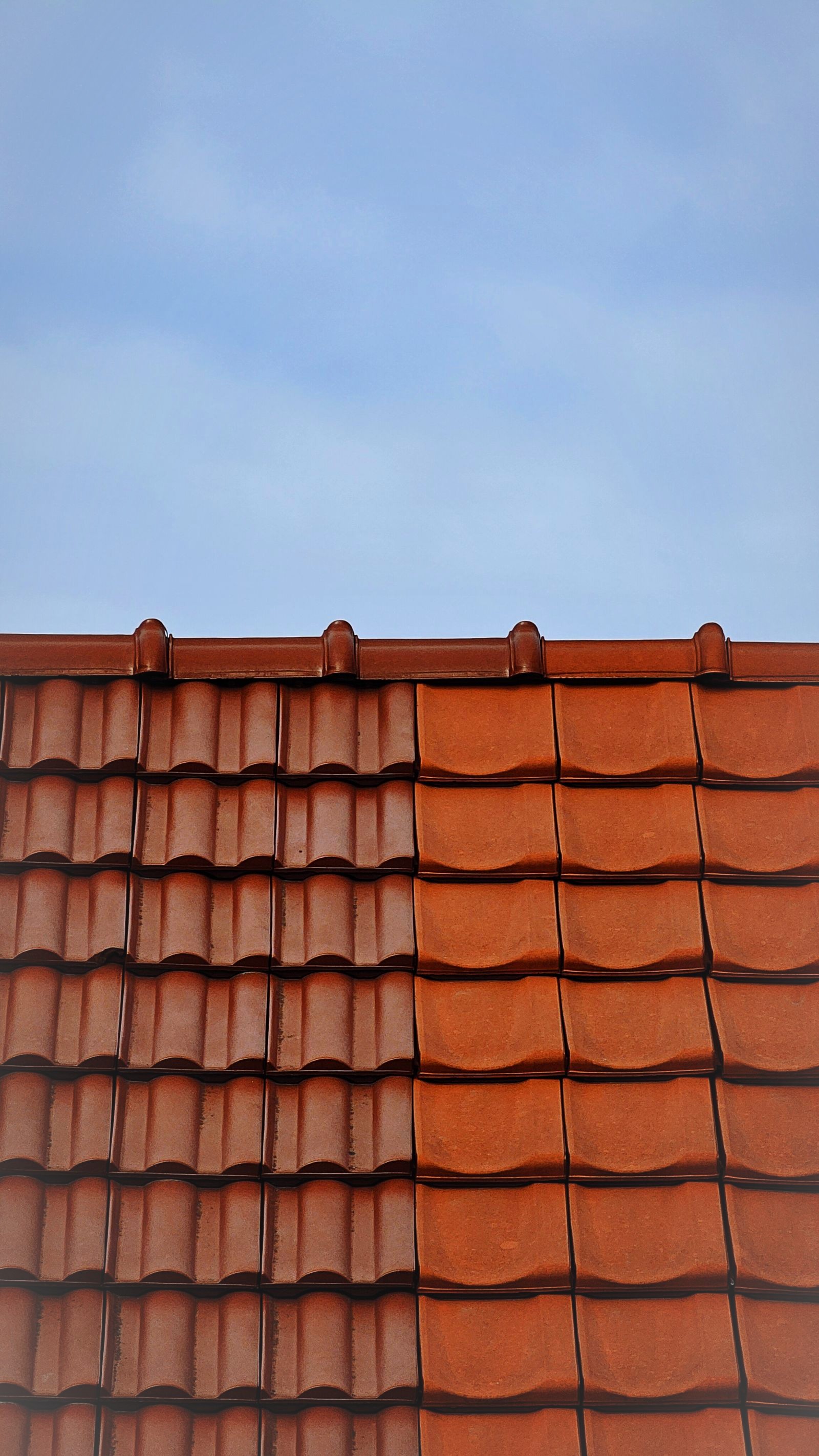Toit de tuiles en terre cuite sous un grand ciel bleu, nos services de toiture à Liège et Saint-Nicolas