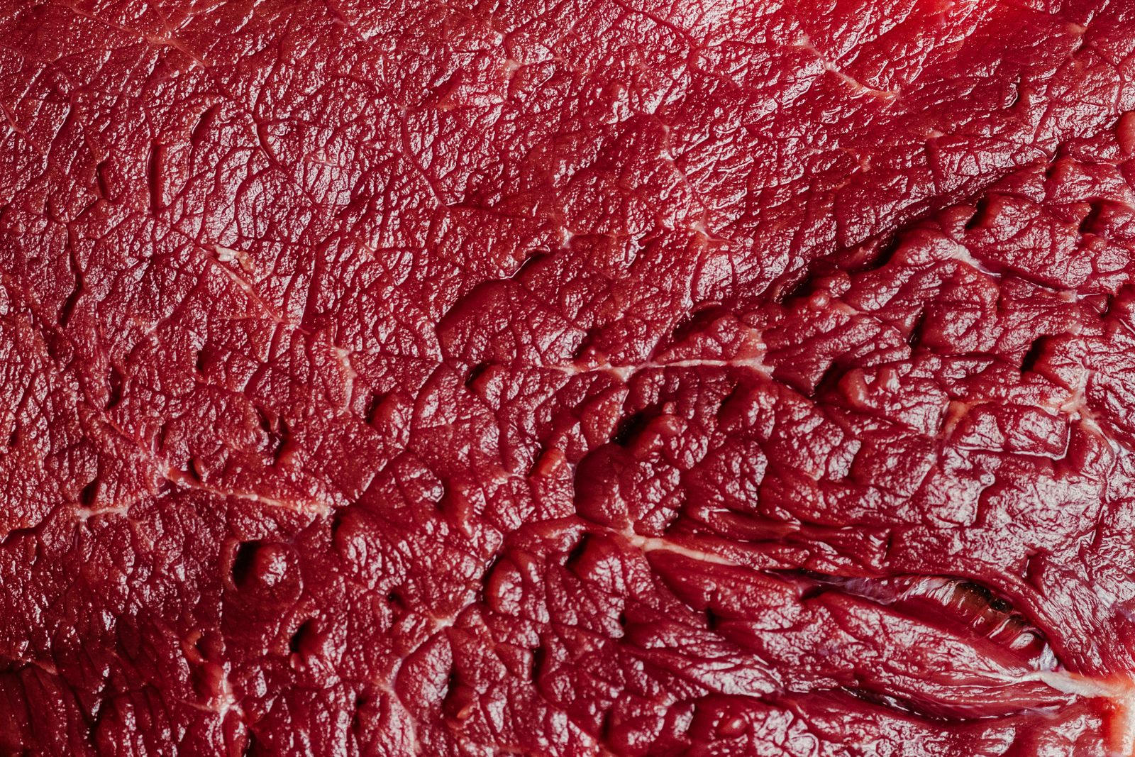 Photo d’illustration — pièce de bœuf crue, persillage visible, planche ou papier boucher, éclairage sombre