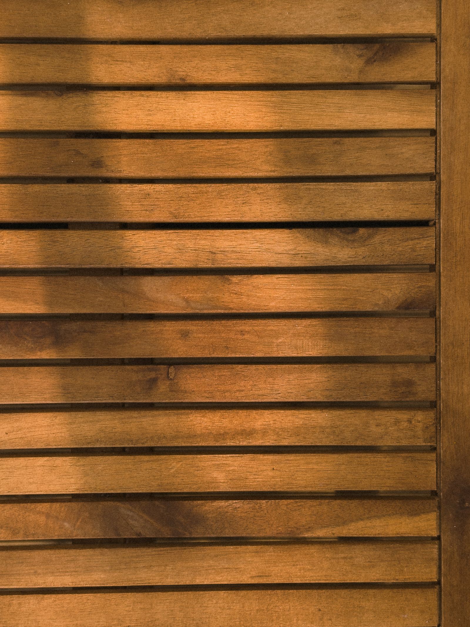 Photo d’illustration — mur de panneaux de bois à lattes clair, lumière chaude, texture graphique